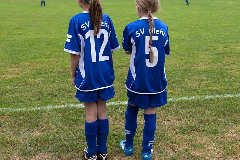 Rückenansicht: zwei junge Fußballspielerinnen stehen am Spielfeldrand und tragen das Trikot vom SV Glehn