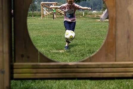 Blick durch die Ballöffnung Torwand: Kind schießt mit einem Fußball auf eine Torwand