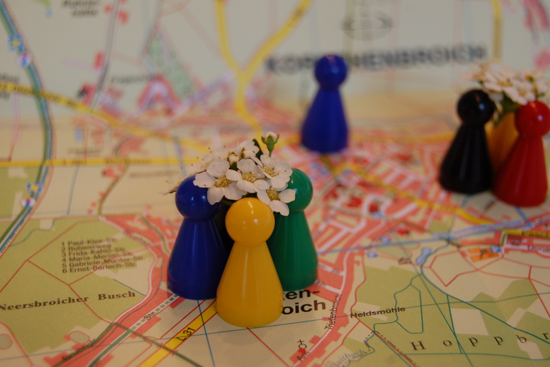 Bunte blumenbekrönte Spielfiguren stehen auf dem Stadtplan eng zusammen 