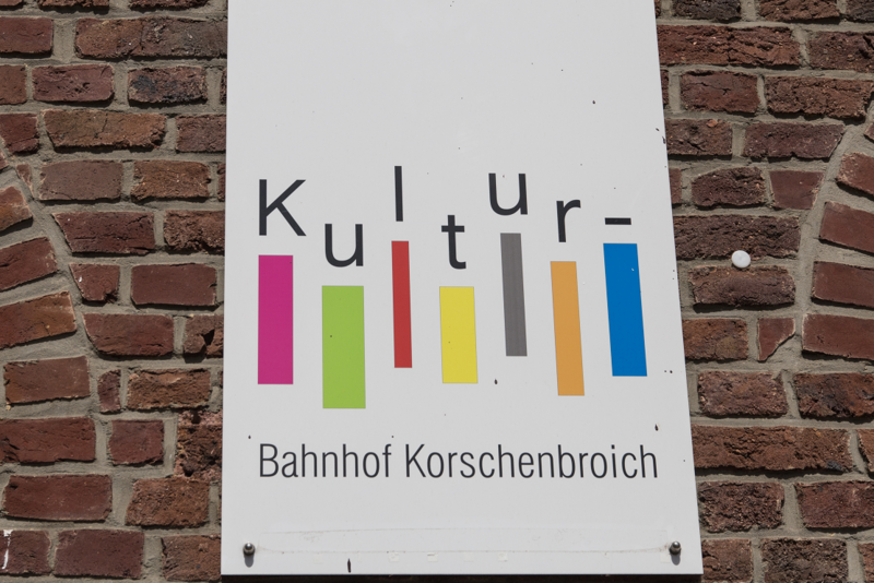 Detailansicht: Schild mit Kulturbahnhof-Logo auf der Bachsteinmauer