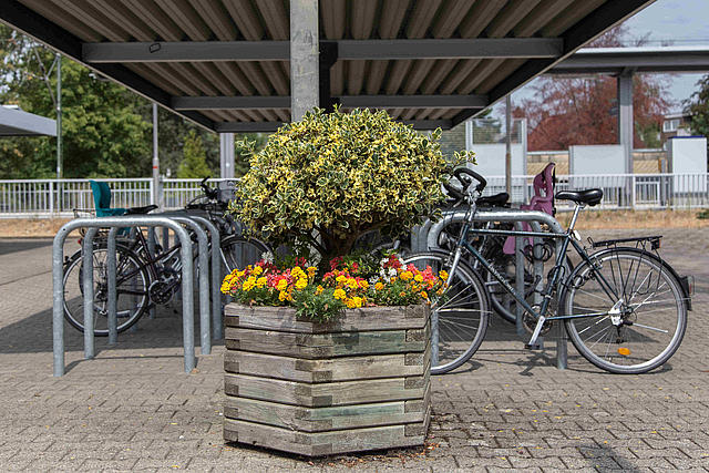 Der Bahnhofsvorplatz in Kleinenbroich: Radständer mit Fahrrädern und im Vordergrund ein Blumenkübel