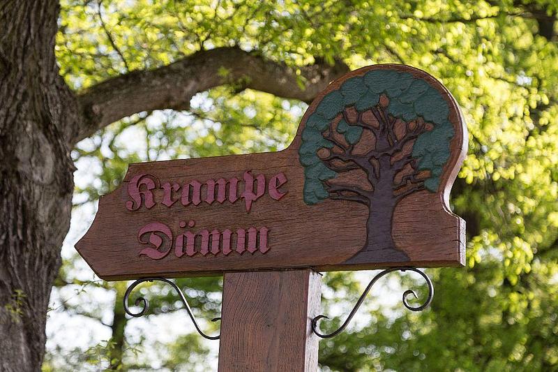 Ein Schild aus Holz mit der Aufschrift "Krampe Dämm".