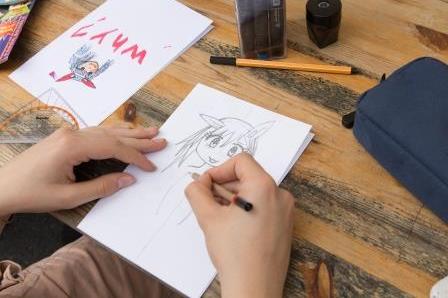 Jugendliche zeichnen Mangas auf Papier.