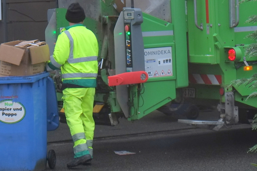 Müllabfuhr sammelt Papierbündel und blaue Tonneninhalte ein