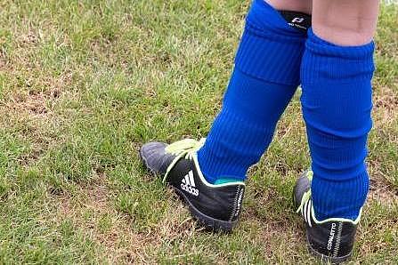 Deatilaufnahme von Kinderbeinen mit Fußballschuhen und Knieschonern